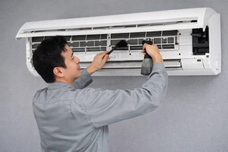 Thợ kỹ thuật đang vệ sinh máy lạnh tại nhà bằng dụng cụ chuyên dụng